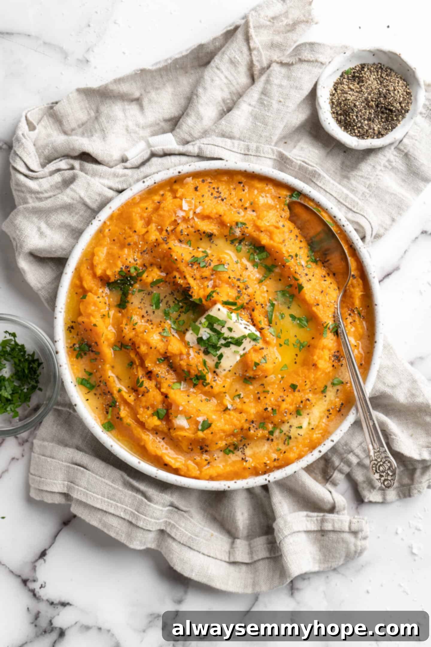 This recipe for vegan mashed sweet potatoes is like a whole holiday celebration in a bowl, but easy enough to make on a busy weeknight! A bowl of creamy mashed sweet potatoes topped with vegan butter and fresh parsley, ready to be served.