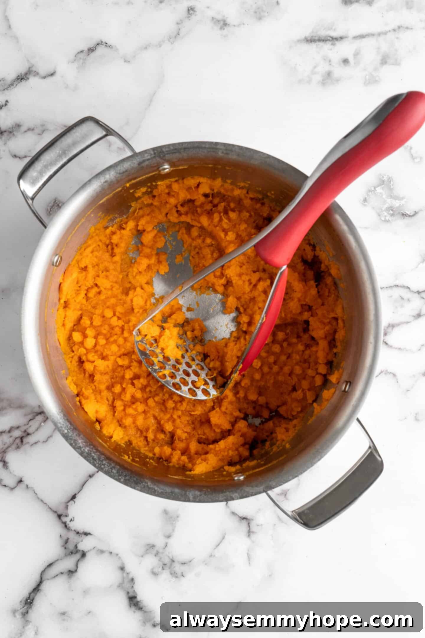 This recipe for vegan mashed sweet potatoes is like a whole holiday celebration in a bowl, but easy enough to make on a busy weeknight! Sweet potato cubes being mashed gently with a potato masher in a pot.