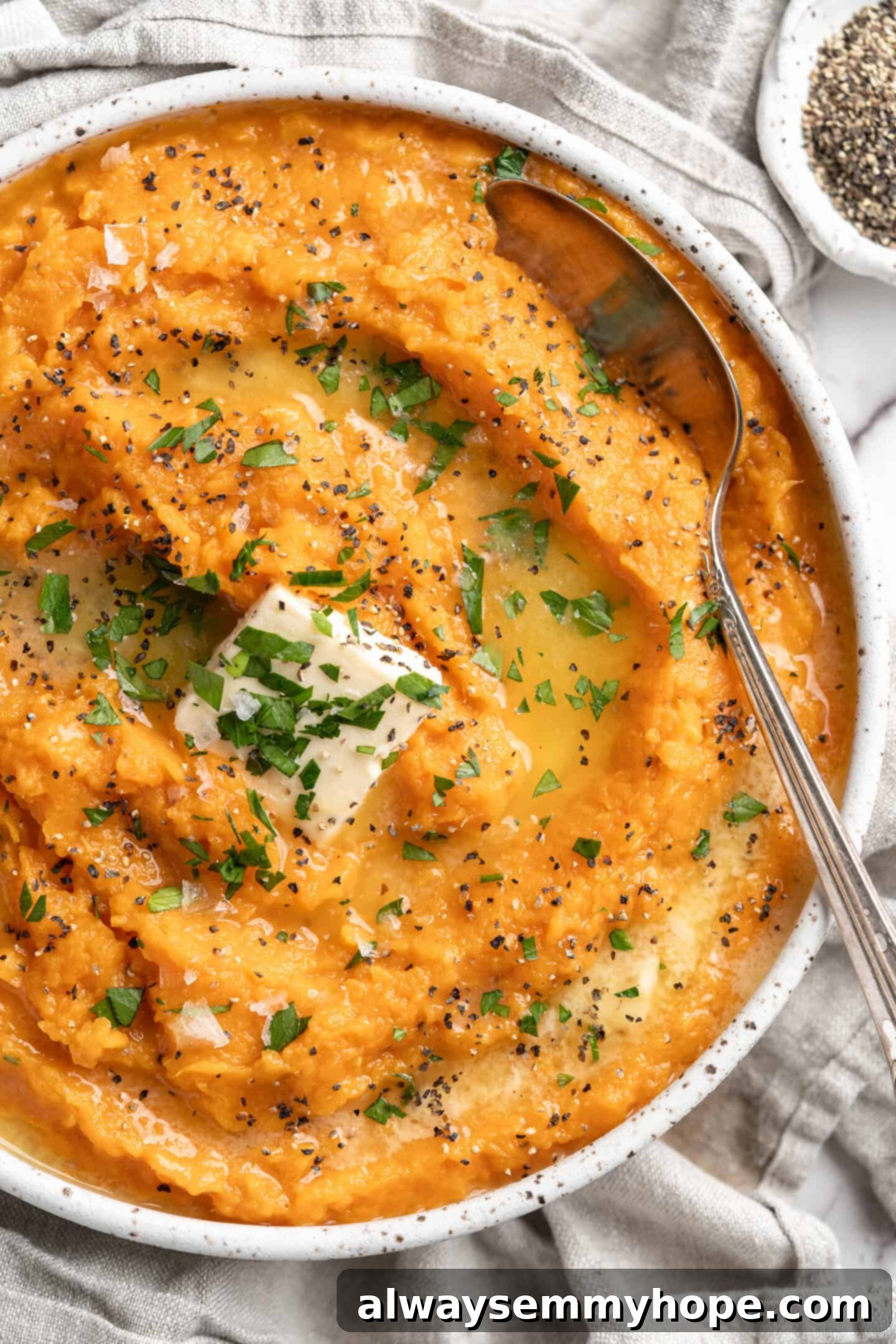 This recipe for vegan mashed sweet potatoes is like a whole holiday celebration in a bowl, but easy enough to make on a busy weeknight! Close-up of creamy mashed sweet potatoes topped with vegan butter and fresh parsley in a bowl.