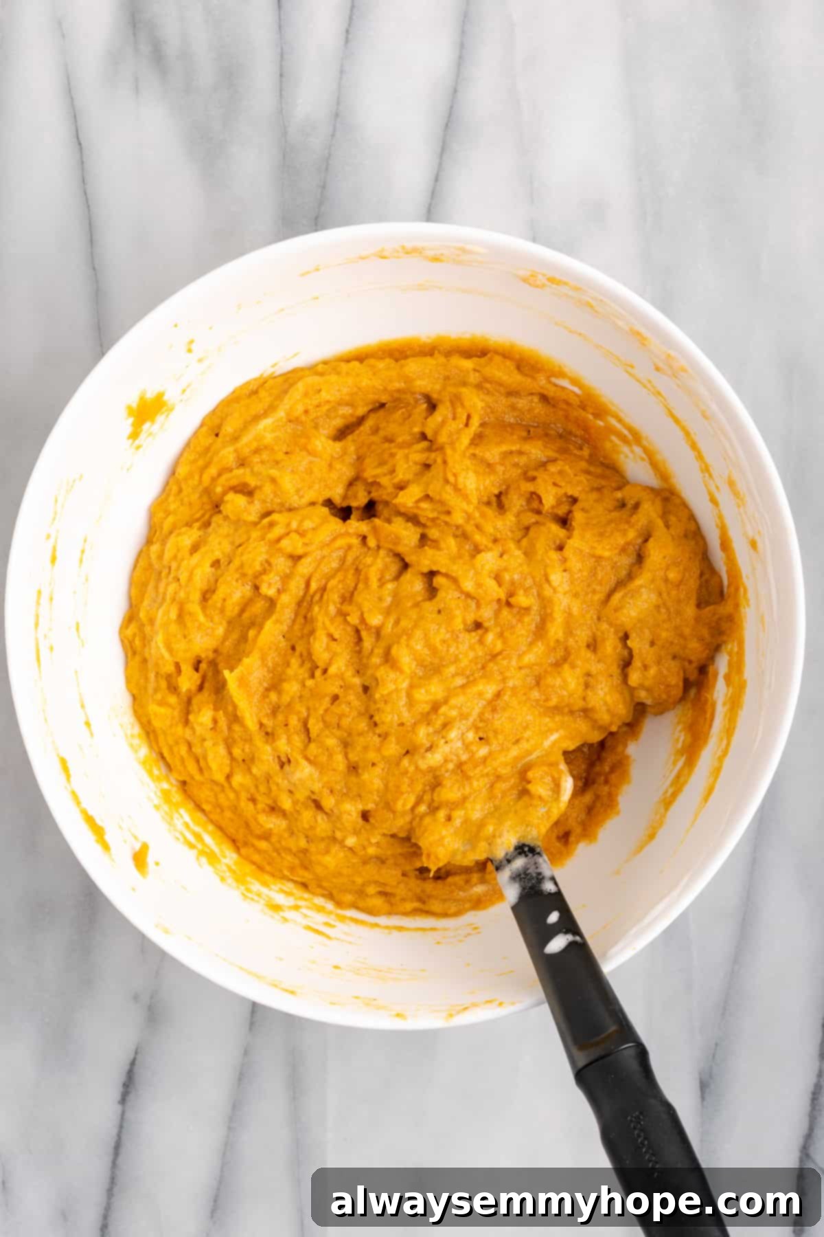 This rich and creamy vegan sweet potato soufflé recipe is a cozy Thanksgiving side. It's entirely vegan, and can easily be made gluten-free. A mixing bowl filled with the light and airy sweet potato soufflé batter, with a whisk resting in the mixture, showcasing its creamy texture.