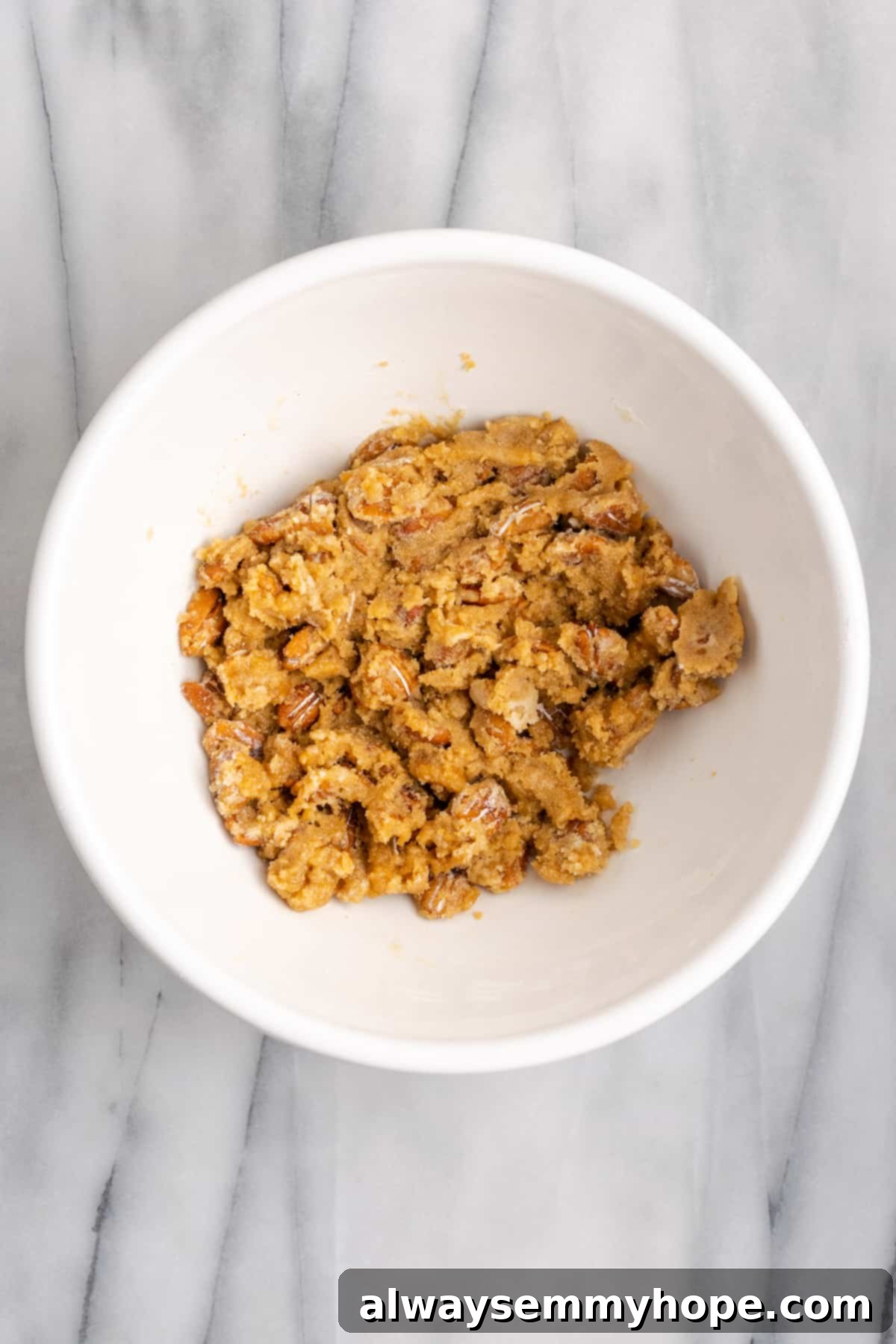 This rich and creamy vegan sweet potato soufflé recipe is a cozy Thanksgiving side. It's entirely vegan, and can easily be made gluten-free. A mixing bowl with the perfectly combined topping ingredients: flour, brown sugar, pecans, and vegan butter, forming a crumbly, irresistible mixture.