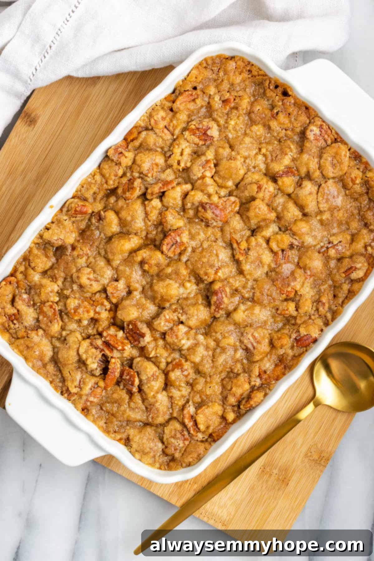 This rich and creamy vegan sweet potato soufflé recipe is a cozy Thanksgiving side. It's entirely vegan, and can easily be made gluten-free. An overhead view of a beautifully baked sweet potato soufflé in a casserole dish, resting on a cutting board next to a golden serving spoon, its topping perfectly golden and inviting.