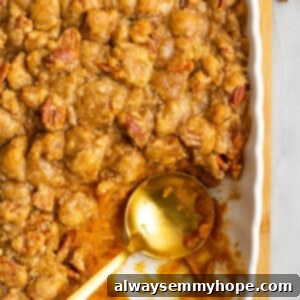 Golden Sweet Potato Delight 3 A casserole dish with sweet potato casserole, with the corner piece missing, and a serving spoon in the casserole dish