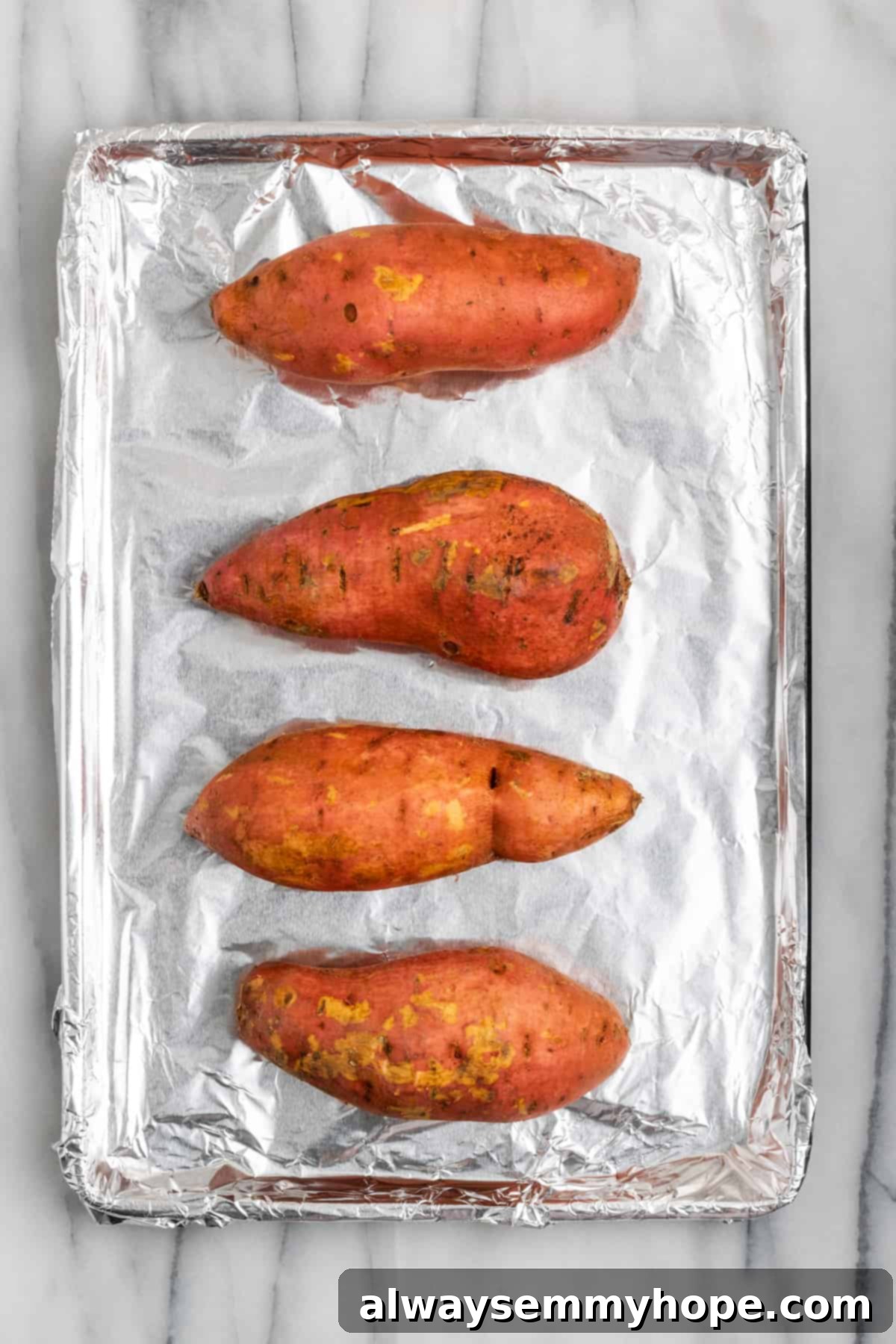 This rich and creamy vegan sweet potato soufflé recipe is a cozy Thanksgiving side. It's entirely vegan, and can easily be made gluten-free. Four raw sweet potatoes resting on a baking sheet lined with aluminum foil, ready for the oven.