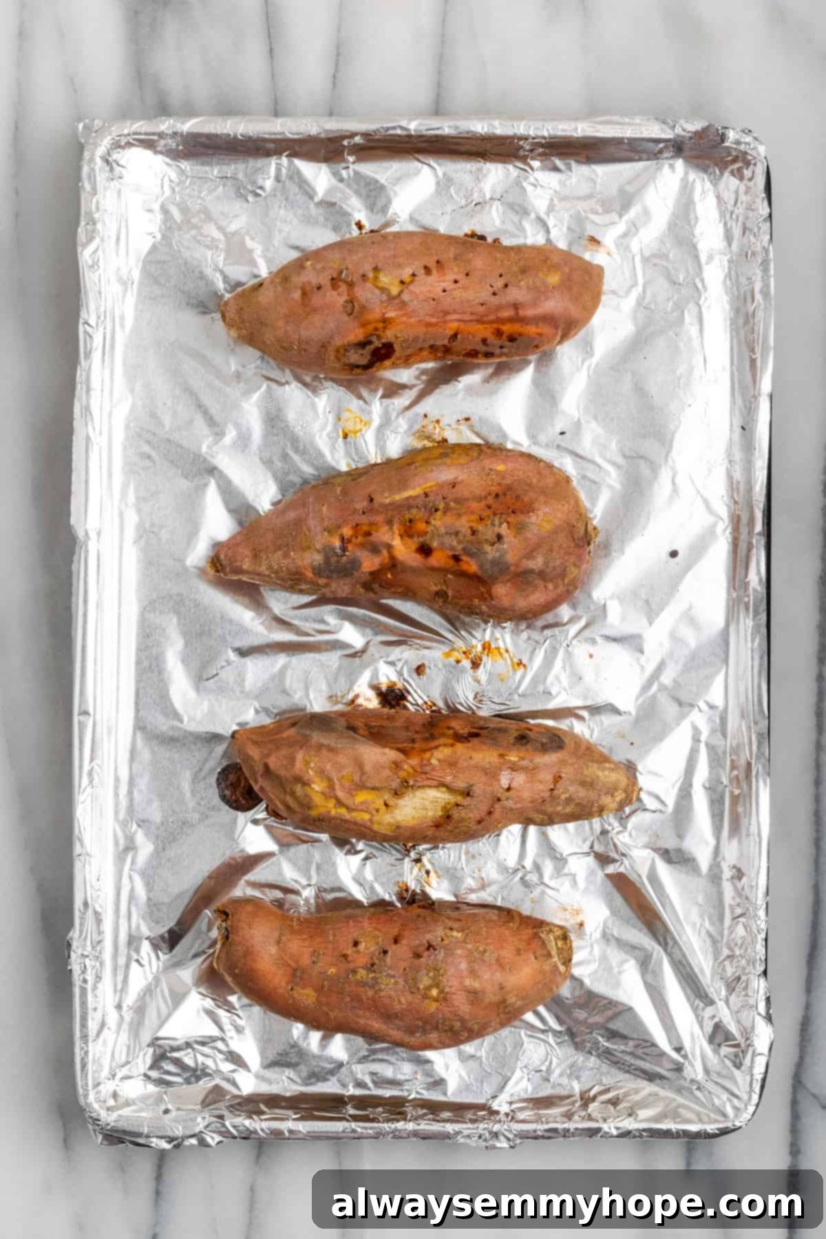 This rich and creamy vegan sweet potato soufflé recipe is a cozy Thanksgiving side. It's entirely vegan, and can easily be made gluten-free. Four perfectly baked sweet potatoes, with softened skins, on an aluminum foil-lined baking sheet, glistening and ready for mashing.