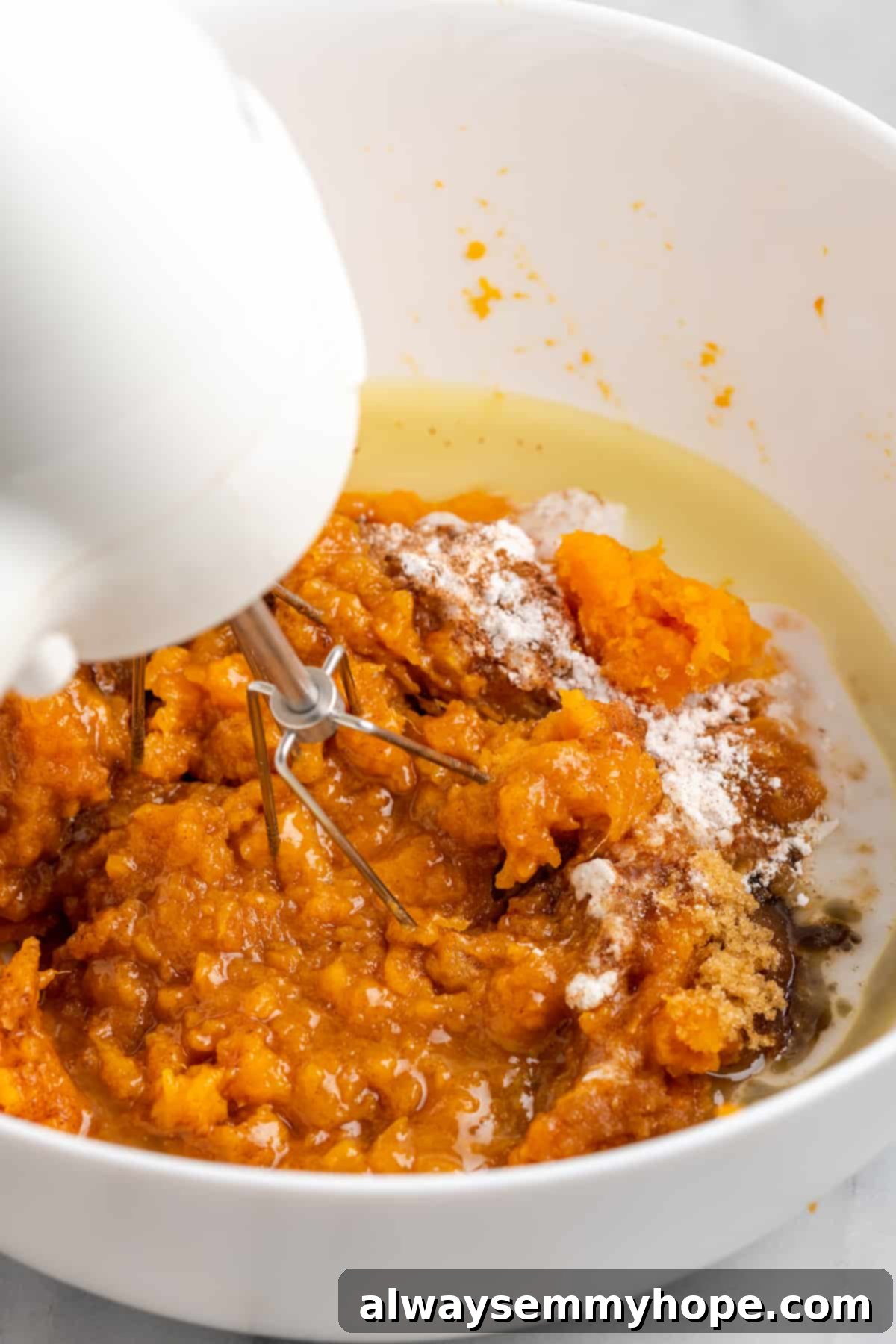 This rich and creamy vegan sweet potato soufflé recipe is a cozy Thanksgiving side. It's entirely vegan, and can easily be made gluten-free. A hand mixer diligently blending together mashed sweet potatoes with rich maple syrup, creamy vegan butter, plant-based milk, and warming spices in a mixing bowl until smooth.