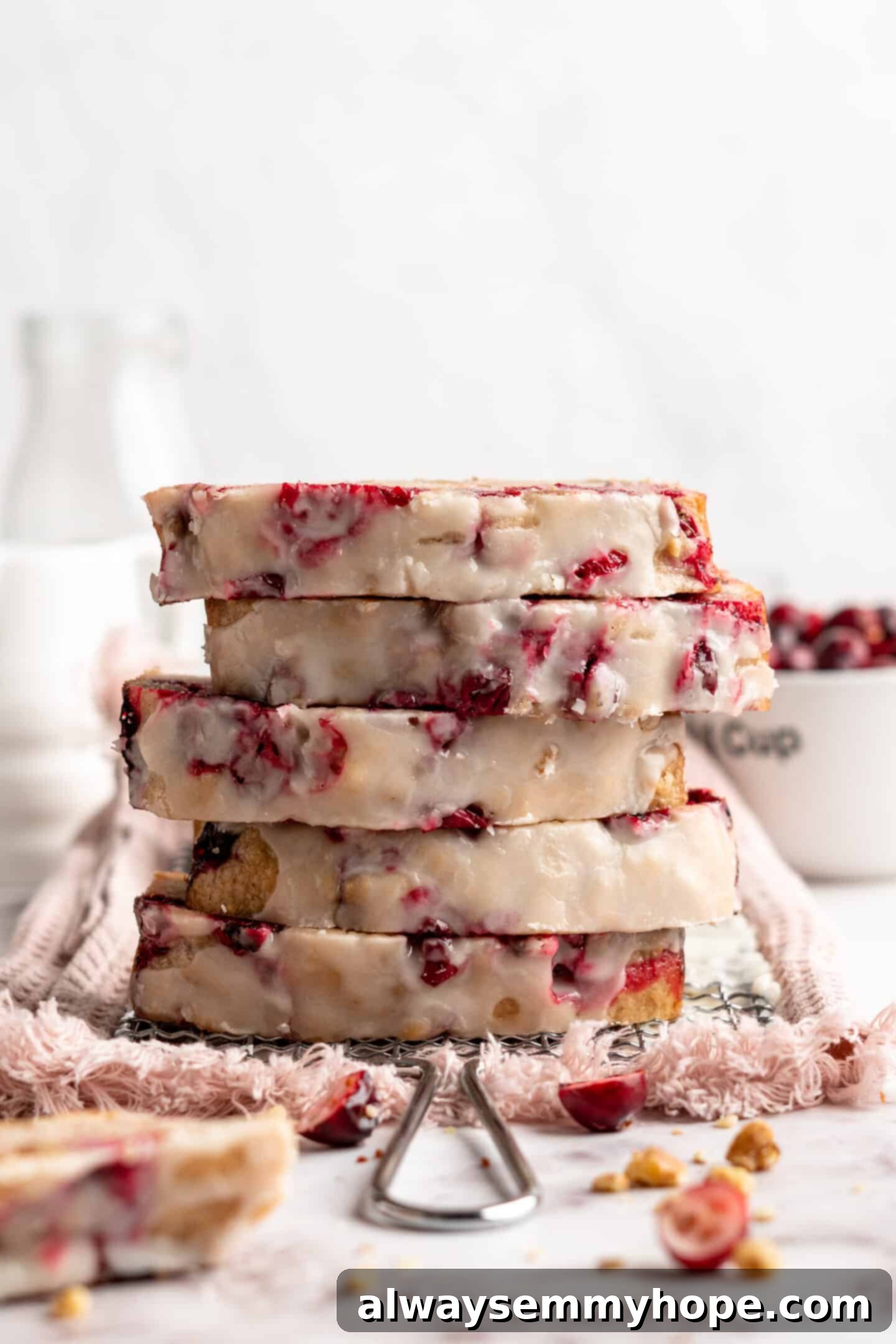 This moist cranberry walnut bread has just the right balance of sweetness, nuttiness, and tartness, and is a perfect holiday treat. A stack of five perfectly baked slices of cranberry orange bread, showcasing their moist texture and even distribution of cranberries.