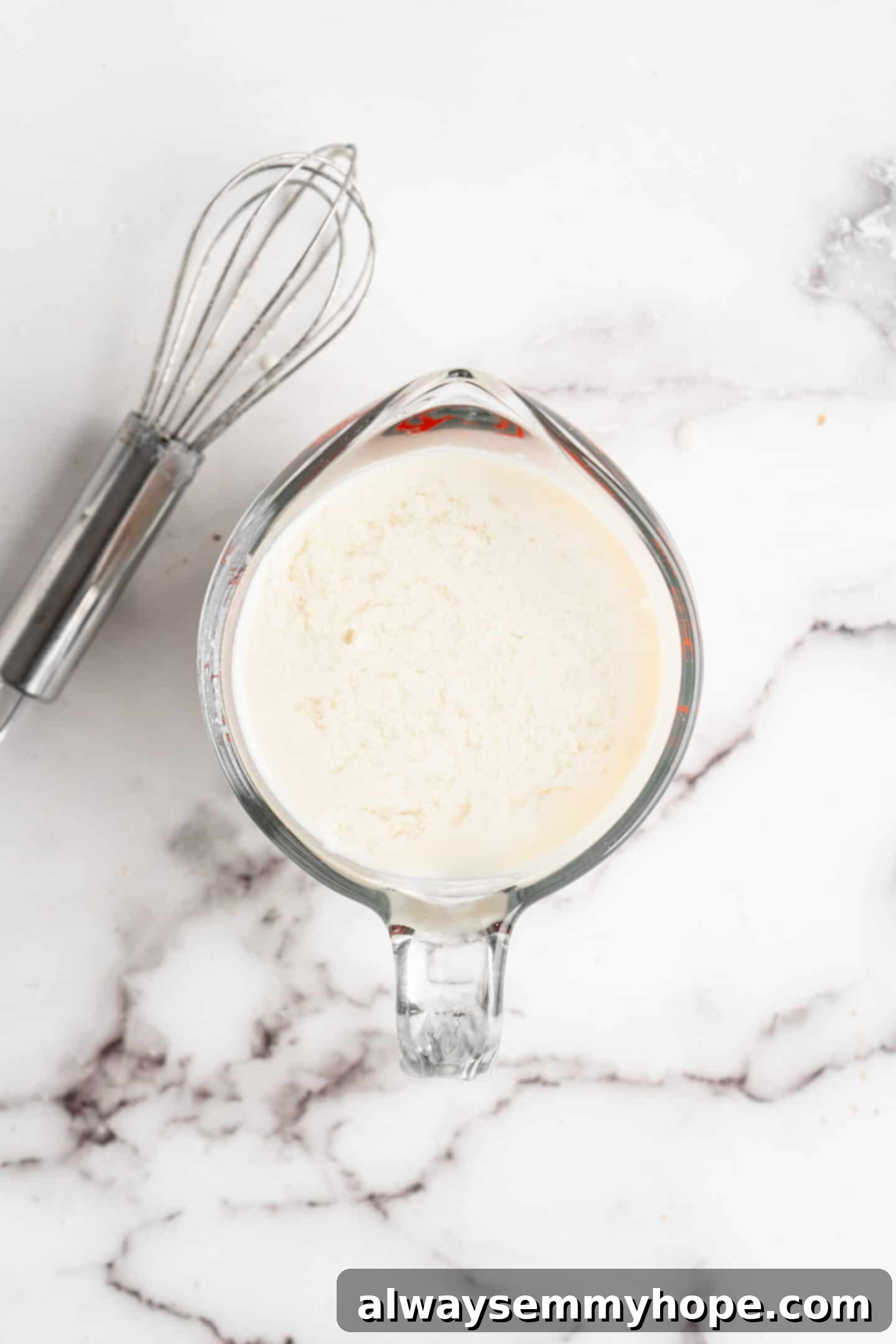 This moist cranberry walnut bread has just the right balance of sweetness, nuttiness, and tartness, and is a perfect holiday treat. A Pyrex measuring dish containing homemade vegan buttermilk, showing the slightly curdled texture, positioned next to a whisk.