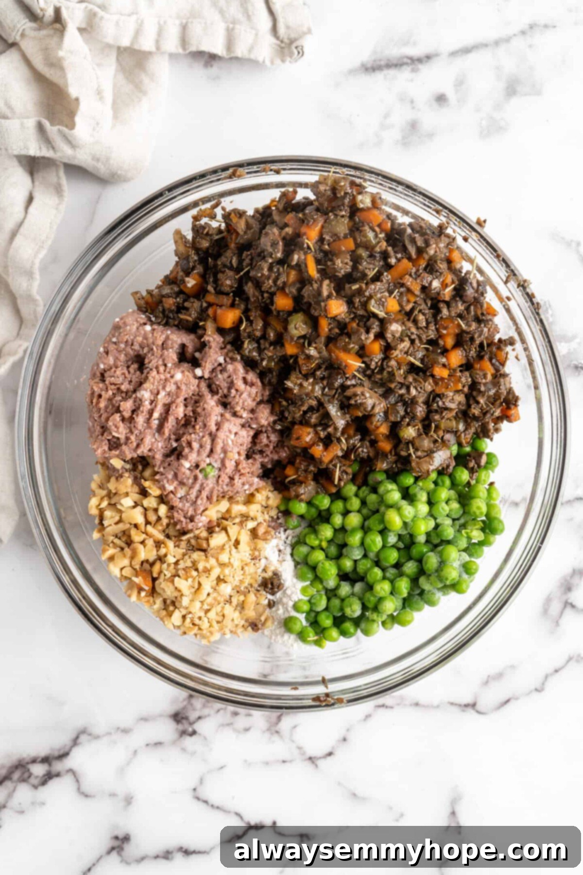 This vegan wellington recipe uses mushrooms, walnuts, and vegan beef to replace meat. It's a hearty holiday meal that's easy to make. A large mixing bowl containing a rich, cooked mushroom and vegetable medley, alongside vibrant frozen peas, finely chopped walnuts, and a block of ground vegan beef, ready to be combined into the savory wellington filling.