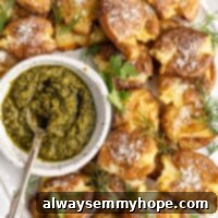 Crispy Air Fryer Potato Smashes 2 Close up of a tray of smashed potatoes with a bowl of pesto, with a spoon in the pesto.