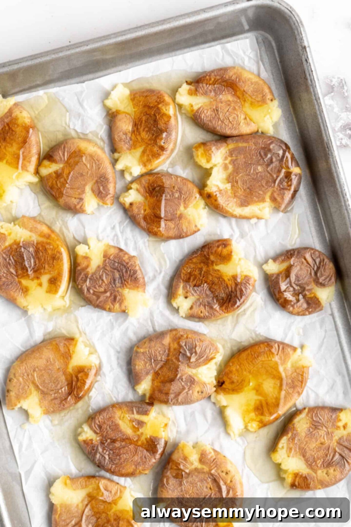 This air fryer smashed potatoes recipe is salty, crispy on the outside, and light and fluffy on the inside. It's an easy side dish, and vegan! A baking sheet full of smashed potatoes covered in olive oil