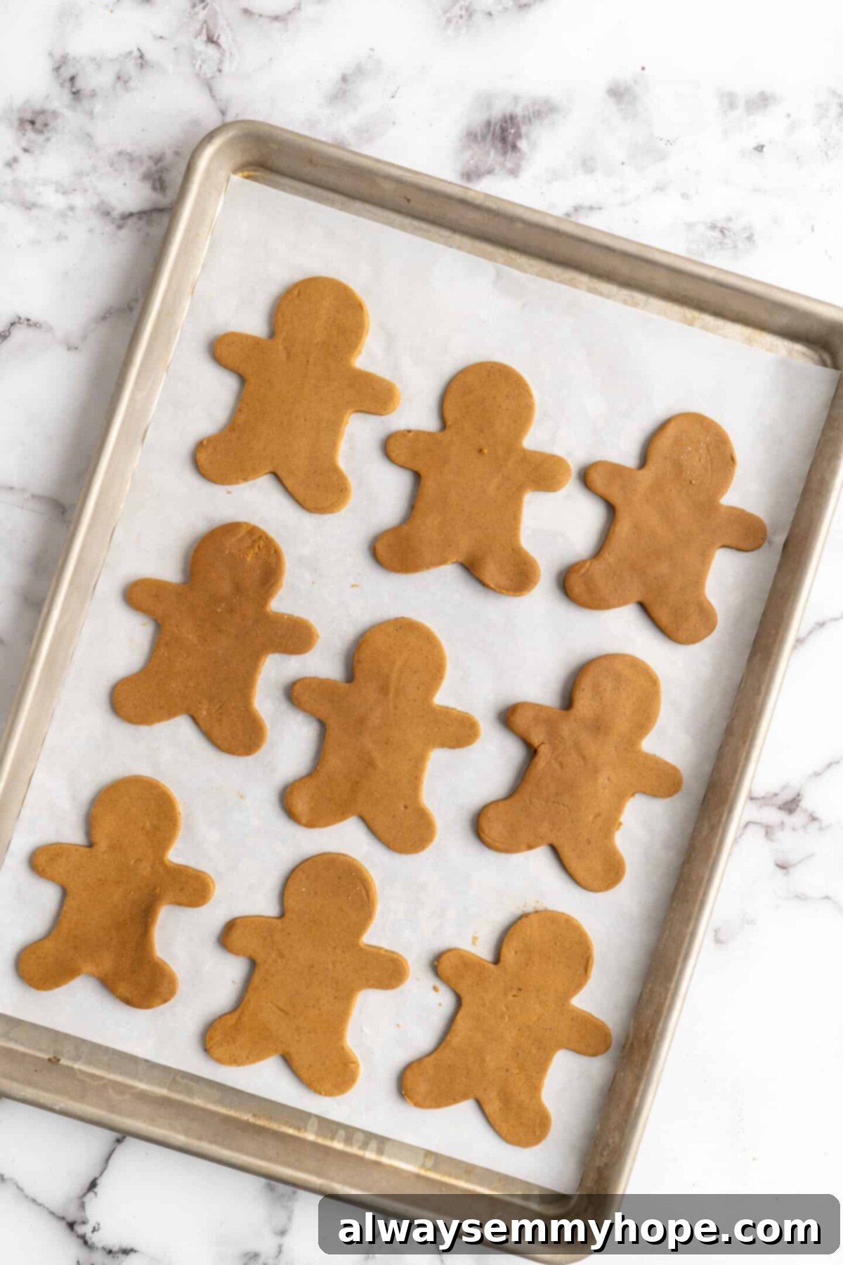 A baking sheet with nine unbaked gingerbread men on it