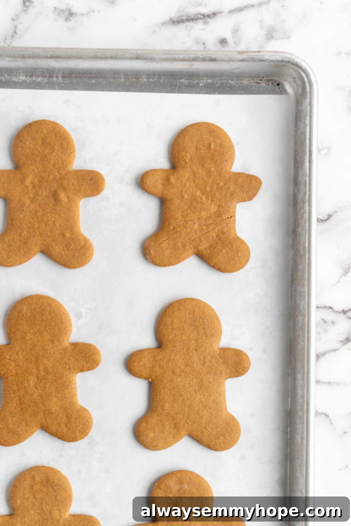 The corner of a baking sheet with cooked gingerbread men on it