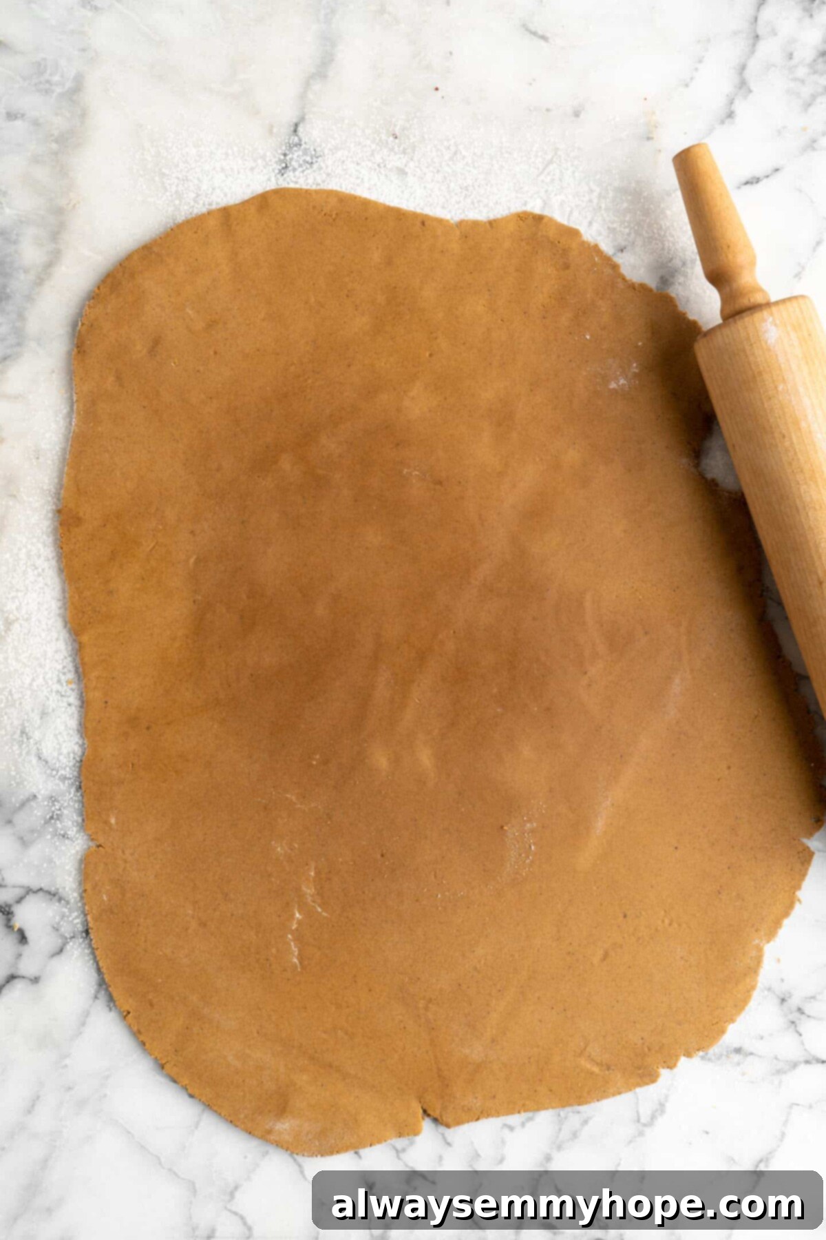 A sheet of gingerbread men dough rolled out, with a rolling pin