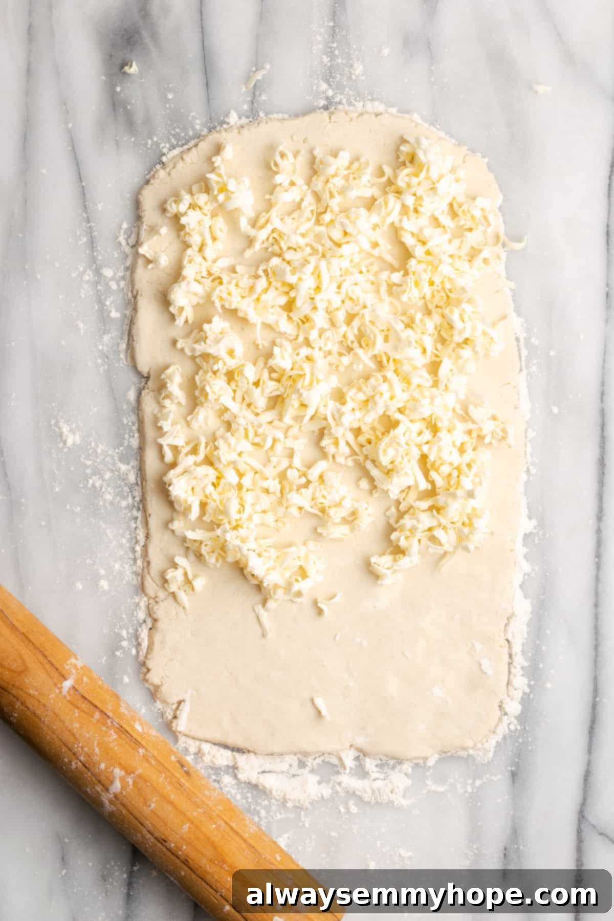 A thin rectangle of dough with shredded butter covering two-thirds of it