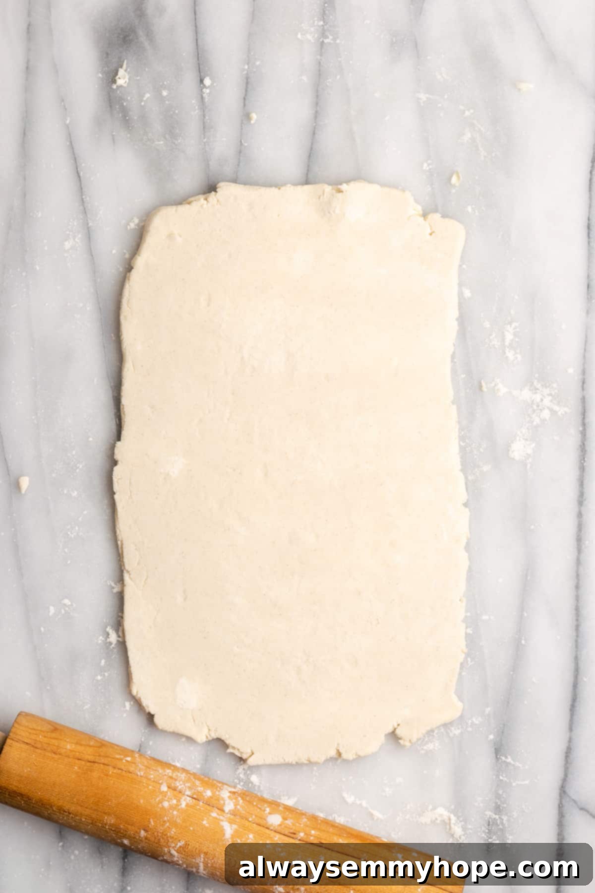 A thick rectangle of dough rolled out next to a rolling pin