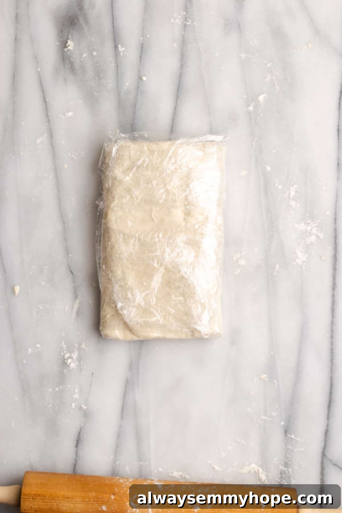 Puff pastry dough folded in an envelope, wrapped in plastic wrap