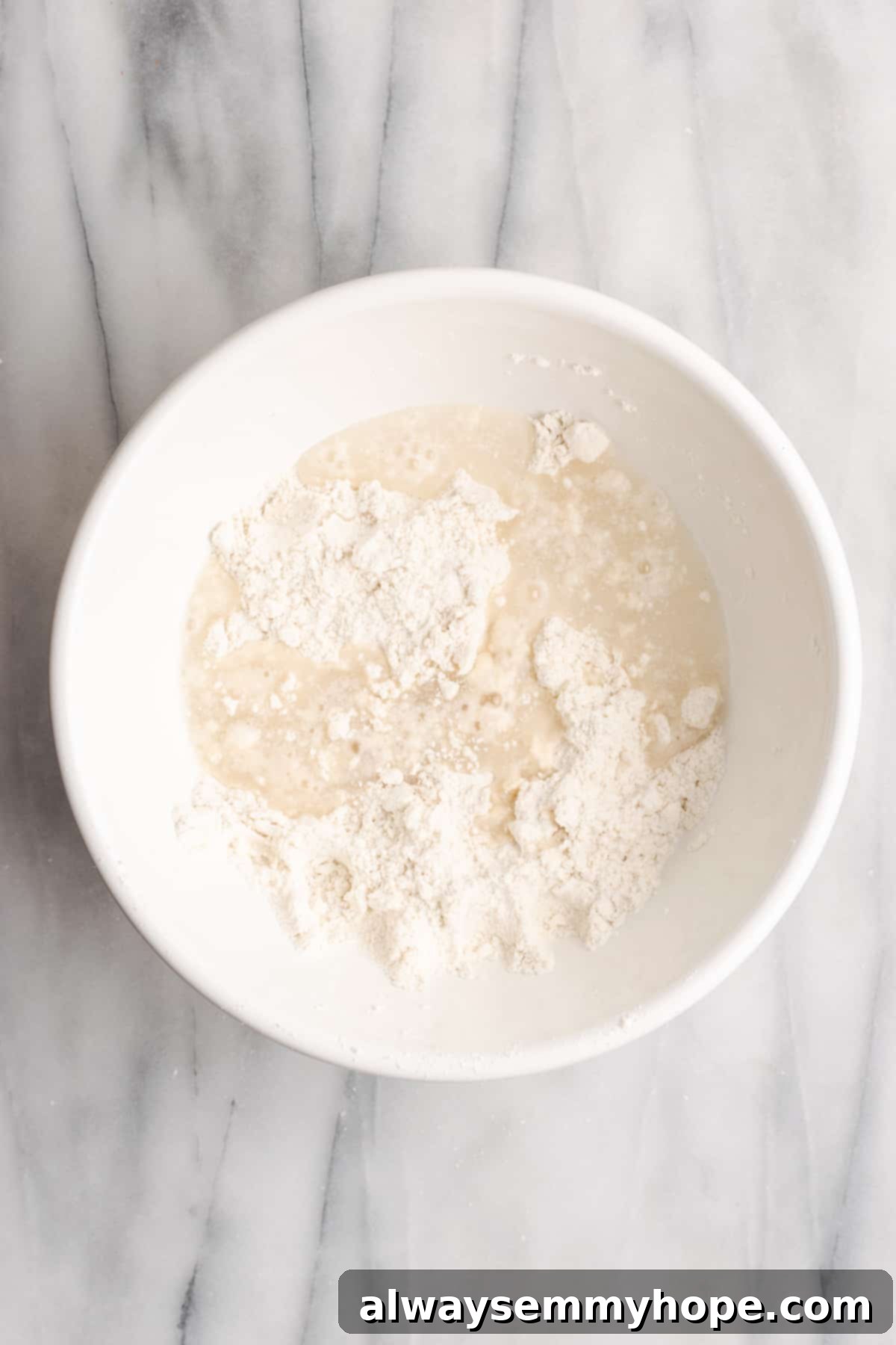 A mixing bowl with flour, pieces of vegan butter, and water