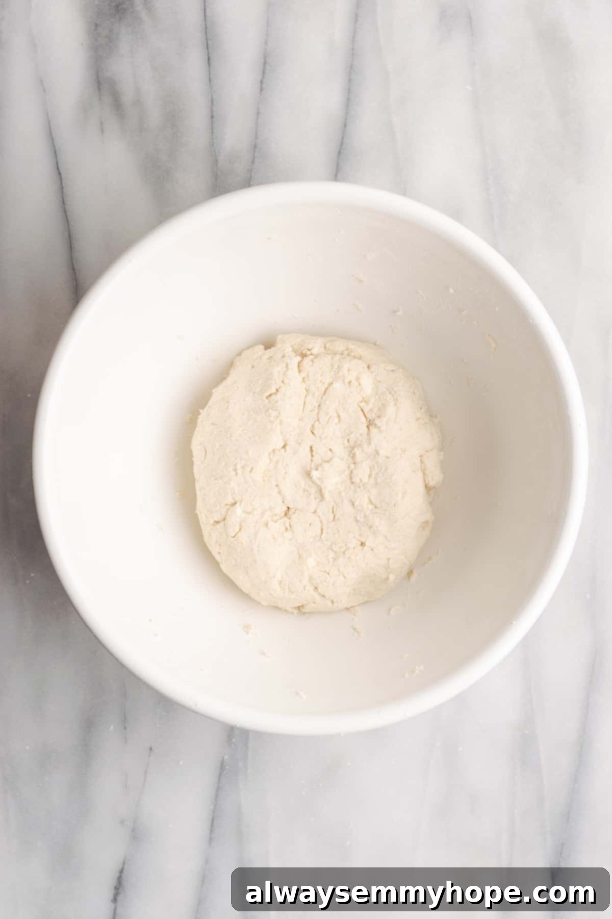 A mixing bowl with a ball of dough in it