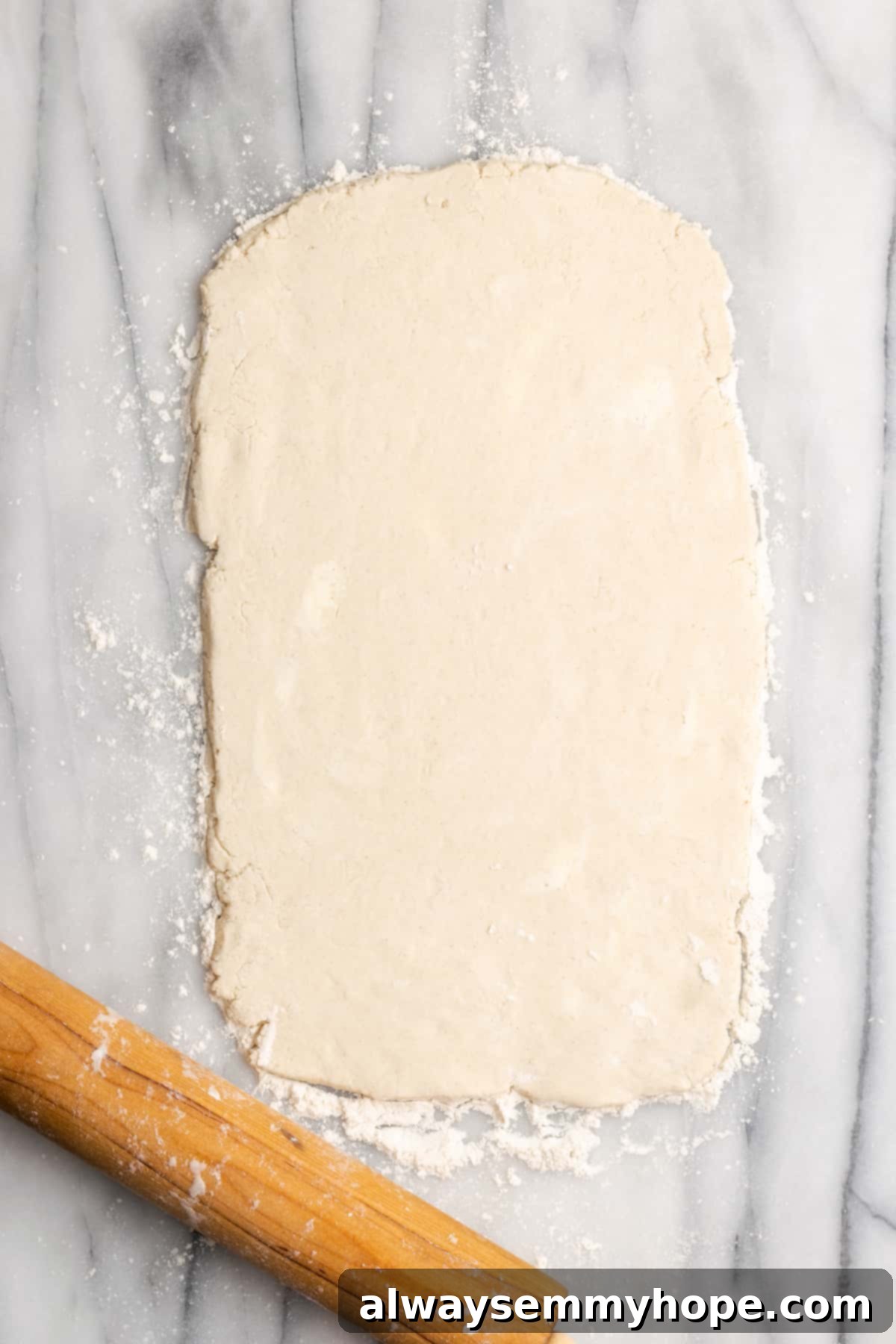 A thin rectangle of dough rolled out next to a rolling pin