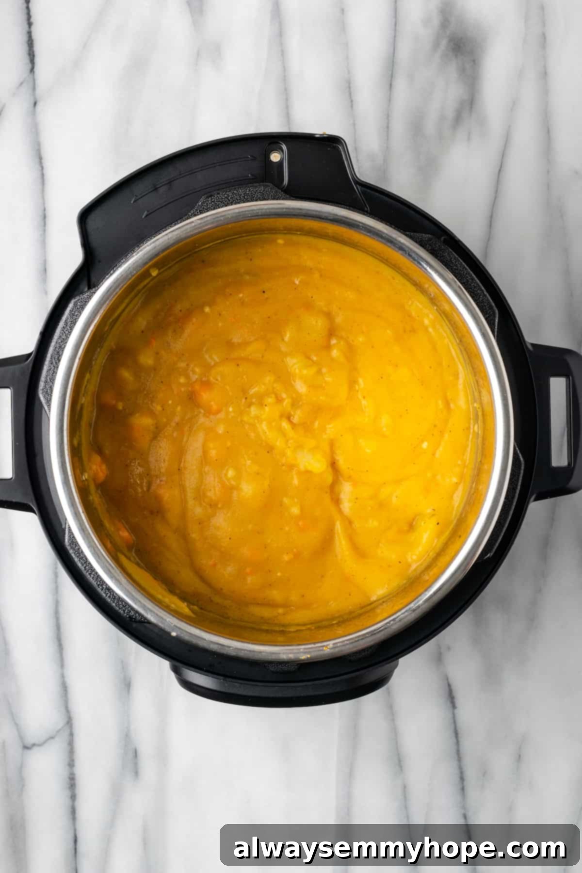 This creamy vegan Instant Pot potato soup recipe is hearty, comforting, and perfect for winter, plus it's easy and quick to make! Blended creamy potato soup in the Instant Pot, showing a smooth texture with hints of orange from the carrots, ready for the final additions.
