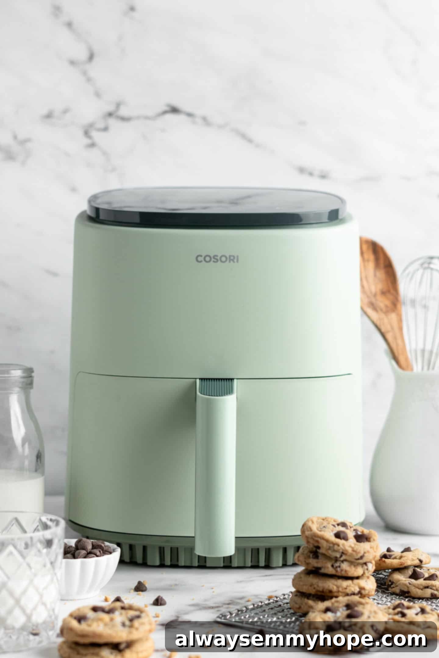 teal coloured Cosori air fryer with perfectly stacked vegan chocolate chip cookies in front of it