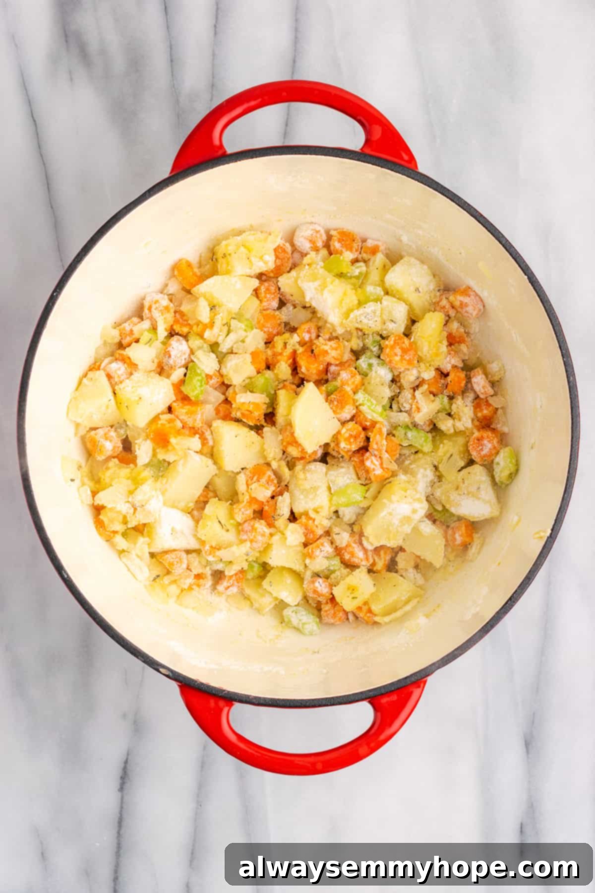 A Dutch oven filled with a thick mixture of vegetables, flour, and seasonings, just before adding the liquids.