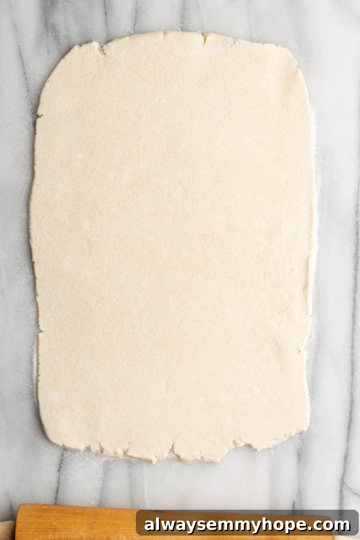 A rectangle of rolled out puff pastry with a rolling pin at the base