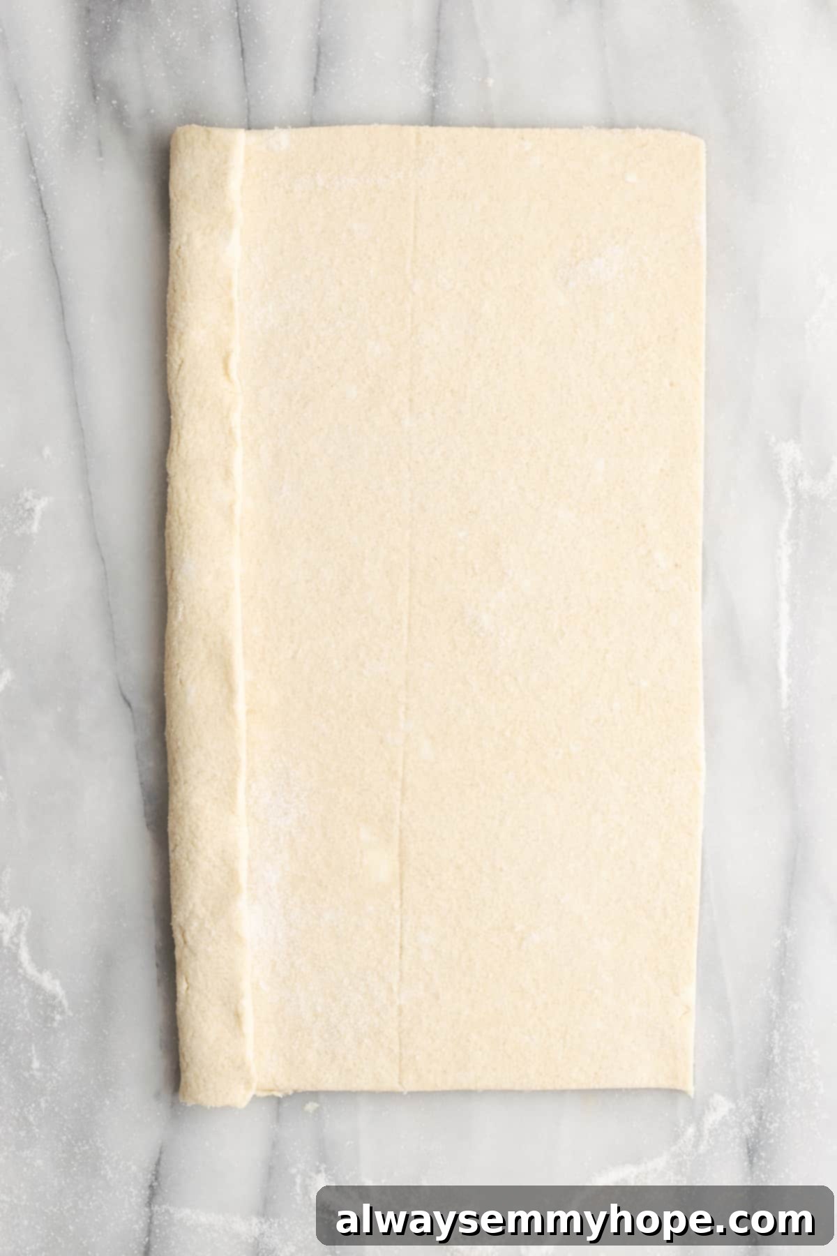 A rectangle of puff pastry dough with one side folded in about a quarter of the way