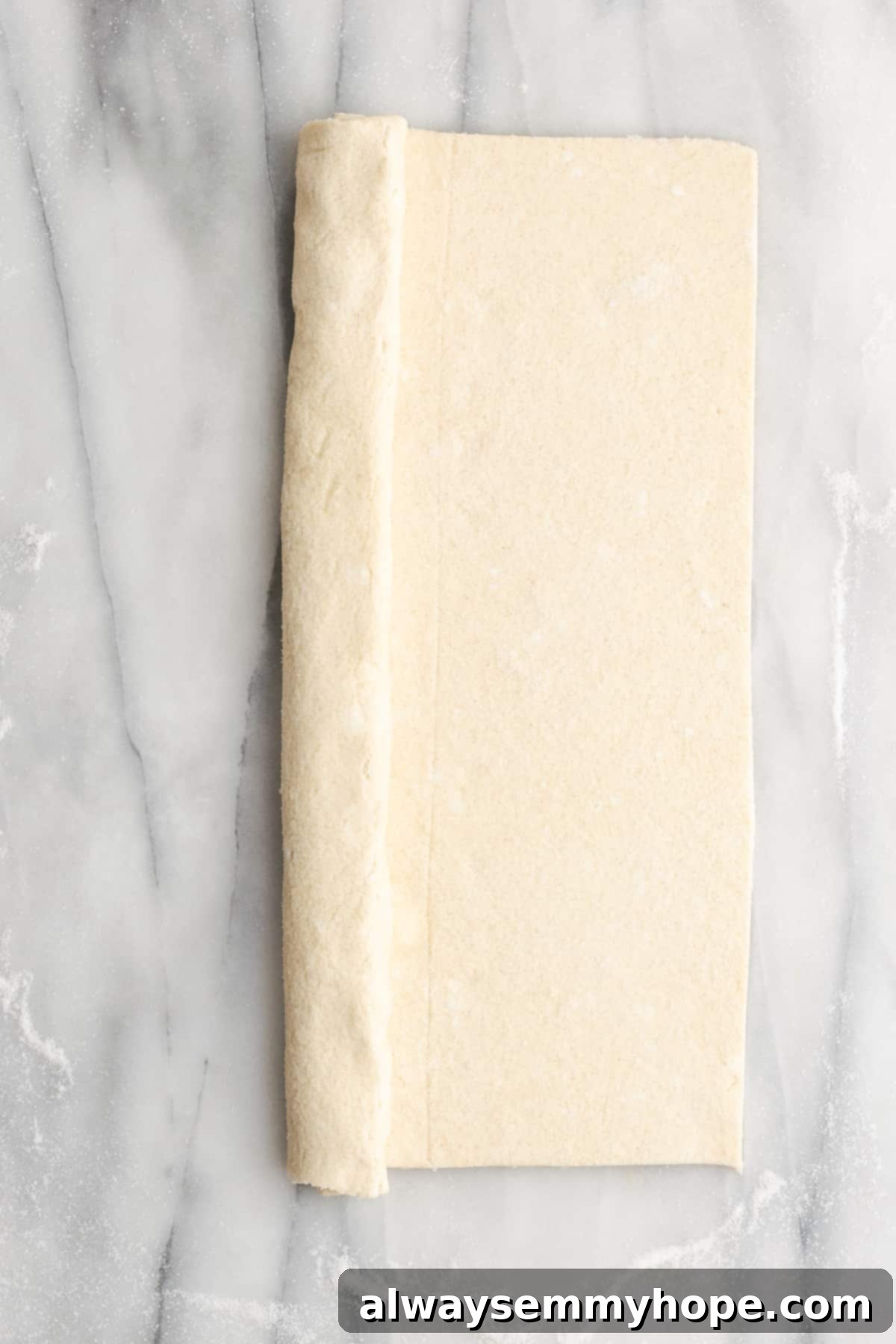 A rectangle of puff pastry with one side folded in towards the middle half way, and the other side not folded