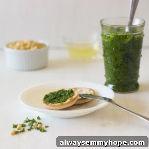 Parsley pesto on crackers with a jar of pesto in the background.