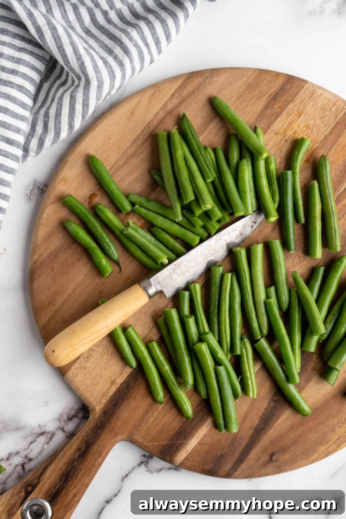 These air fryer green beans are seasoned to perfection and air fried until crispy for an easy side dish that goes with anything! Fresh green beans on a wooden cutting board with a knife next to them, ready for trimming.