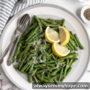 Crispy Air Fryer Green Beans 2 Overhead view of air fryer green beans on plate with spoon, fork, and lemon wedges