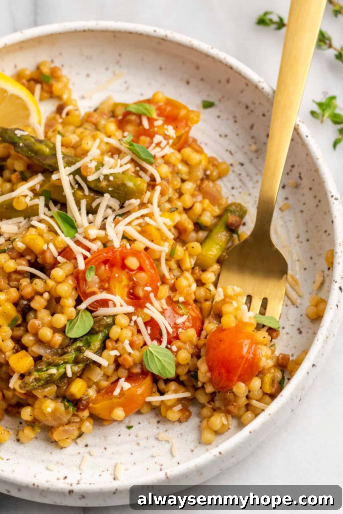 Close-up overhead shot of a single serving of veggie fregola on a white plate, highlighting its texture and fresh ingredients.