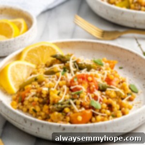 Vegan fregola sarda on plate with lemon wedges, garnished with fresh herbs.