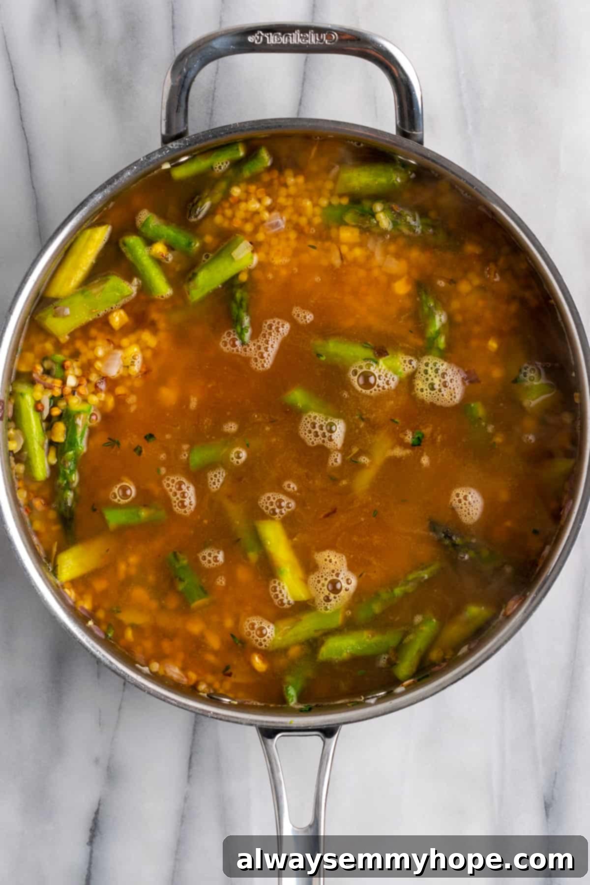 Vegetable stock being poured into the pan of toasted fregola and vegetables, ready for cooking.