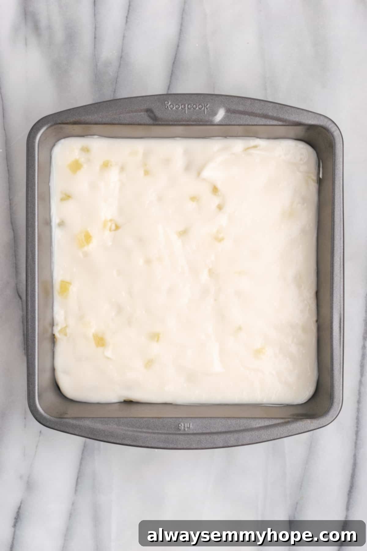 Hawaiian Coconut Haupia 11 Overhead view of smooth haupia mixture poured into an 8x8 metal pan, before adding the remaining pineapple topping.