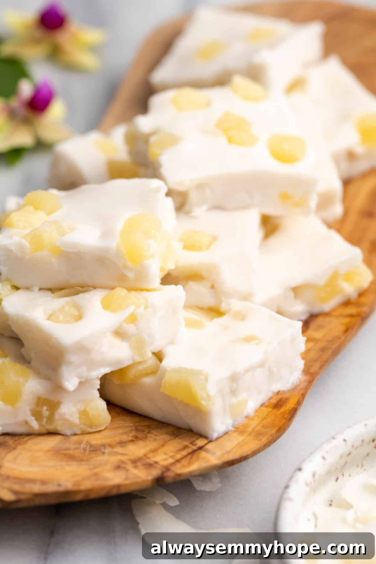 Hawaiian Coconut Haupia 14 Neatly stacked haupia slices on a wooden platter, showcasing the firm texture and vibrant pineapple inclusions.