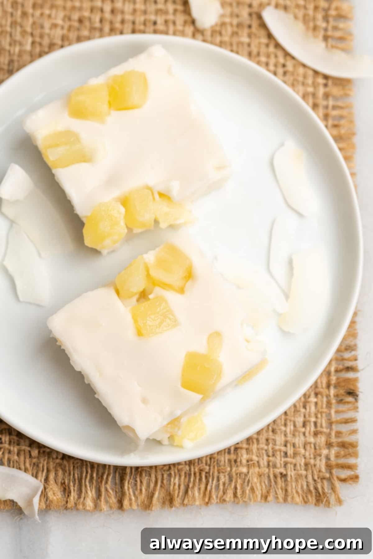 Hawaiian Coconut Haupia 5 Two vibrant slices of pineapple haupia on a crisp white plate, showcasing the embedded pineapple pieces and smooth texture.