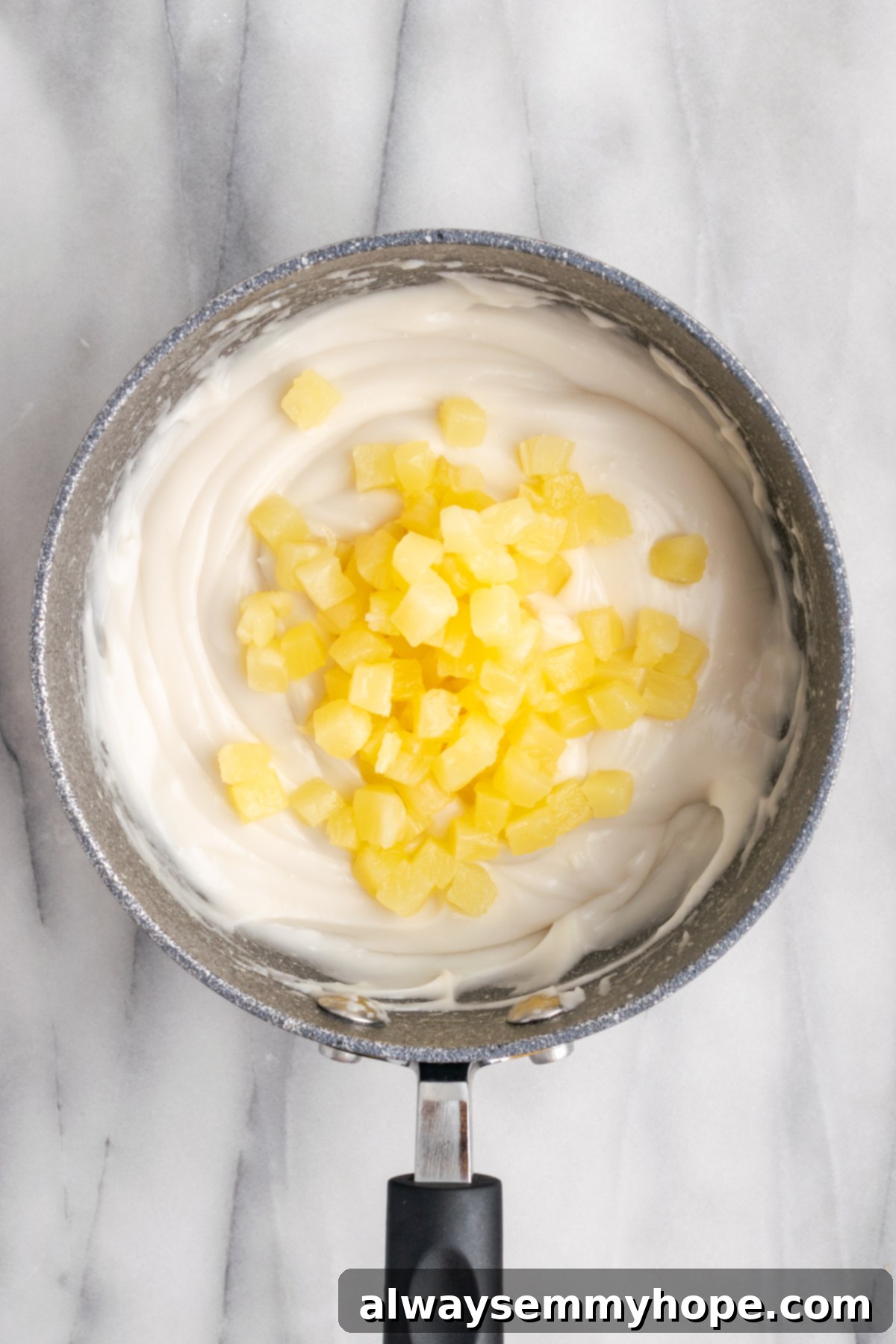 Hawaiian Coconut Haupia 9 Pineapple tidbits being gently added to the thickened haupia mixture in a pan.