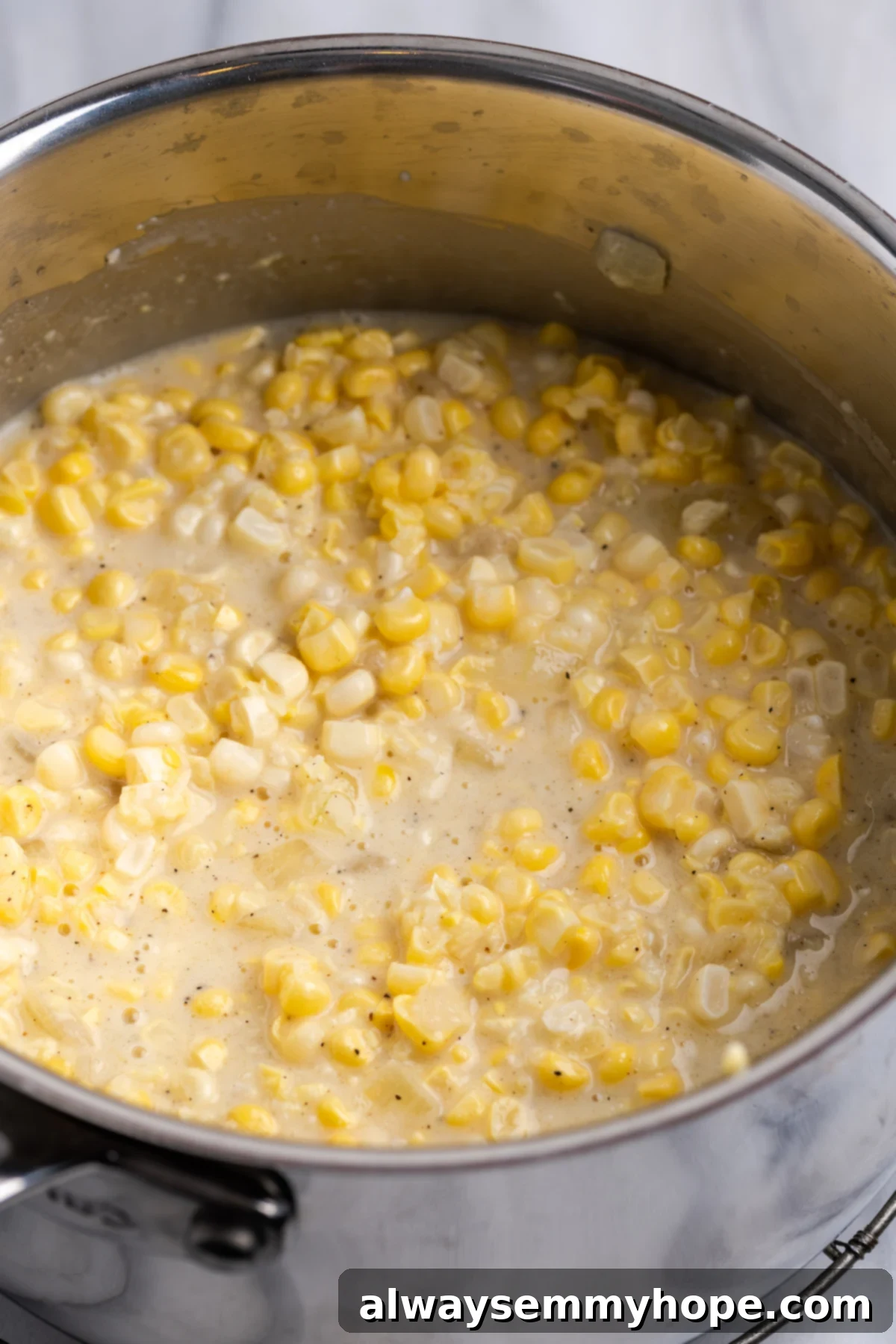 My recipe for vegan creamed corn is an easy way to make this crowd-pleasing side dish without the dairy milk and butter! Vegan creamed corn simmering gently in a pot, thickening into a creamy sauce