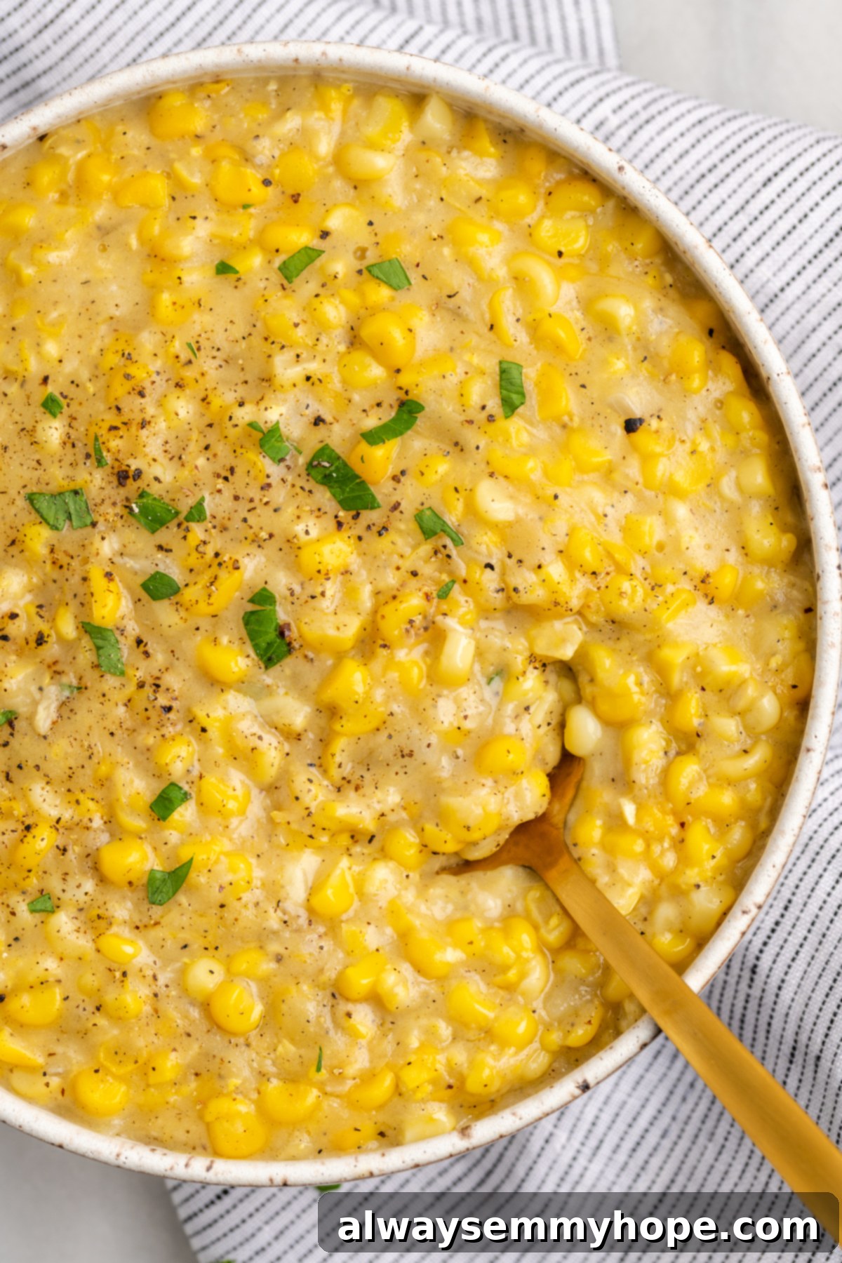 Overhead view of vegan creamed corn in serving bowl with gold spoon