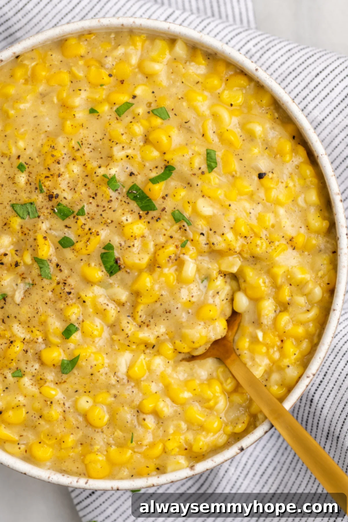 My recipe for vegan creamed corn is an easy way to make this crowd-pleasing side dish without the dairy milk and butter! Overhead view of vegan creamed corn in a serving bowl with a gold spoon