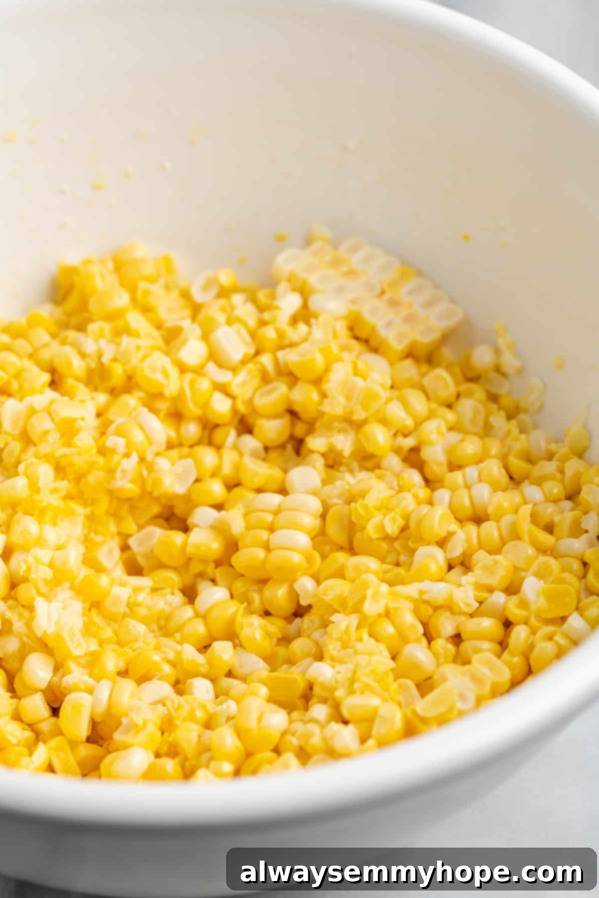 My recipe for vegan creamed corn is an easy way to make this crowd-pleasing side dish without the dairy milk and butter! Fresh yellow corn kernels, pulp, and juice in a white bowl