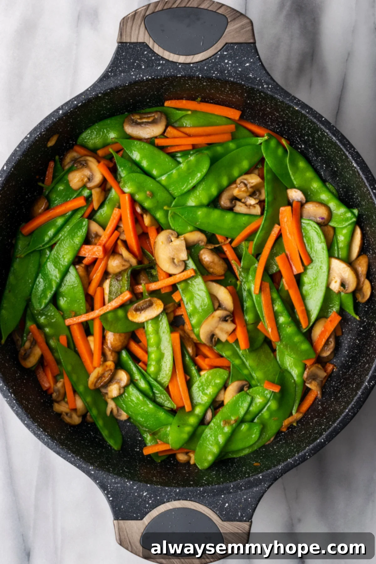 Stir-fried to perfection: Tender-crisp vegetables for a fresh and flavorful vegan Chow Fun. Overhead view of stir-fried carrots, mushrooms, and snow peas, perfectly tender-crisp in the pan.