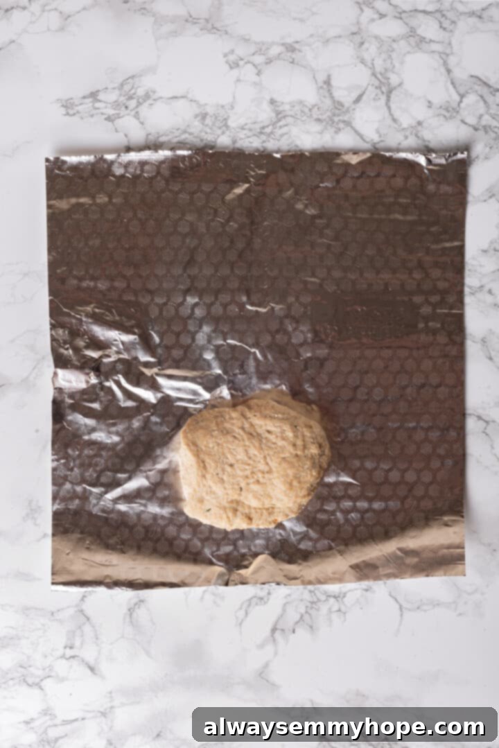 An uncooked homemade vegan chicken piece placed on a large sheet of aluminum foil, ready for wrapping.