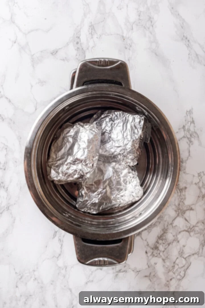 Wrapped vegan chicken pieces placed inside a steamer basket in a large pot, ready for steaming.
