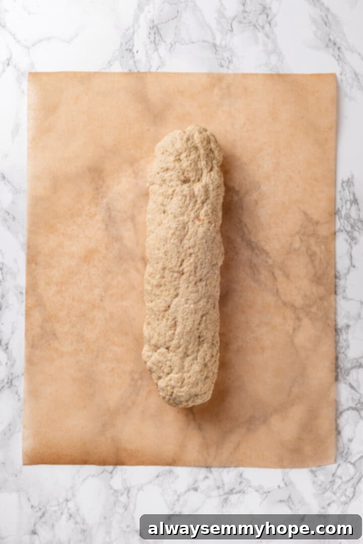 Vegan chicken dough shaped into a uniform log on a cutting board.
