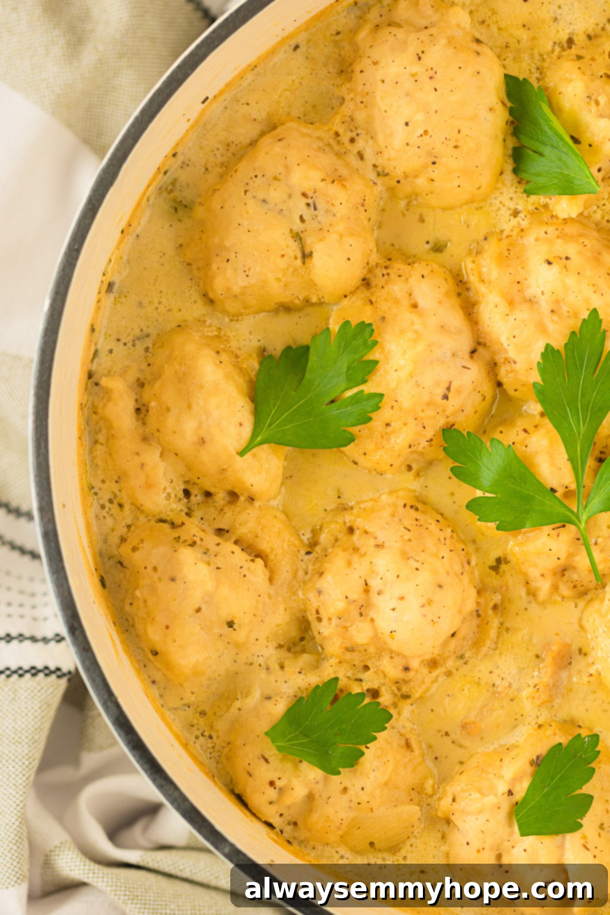 A large Dutch oven filled with simmering vegan chicken and dumplings, steam rising appetizingly. Rich and creamy vegan chicken and dumplings bubbling in a Dutch oven.
