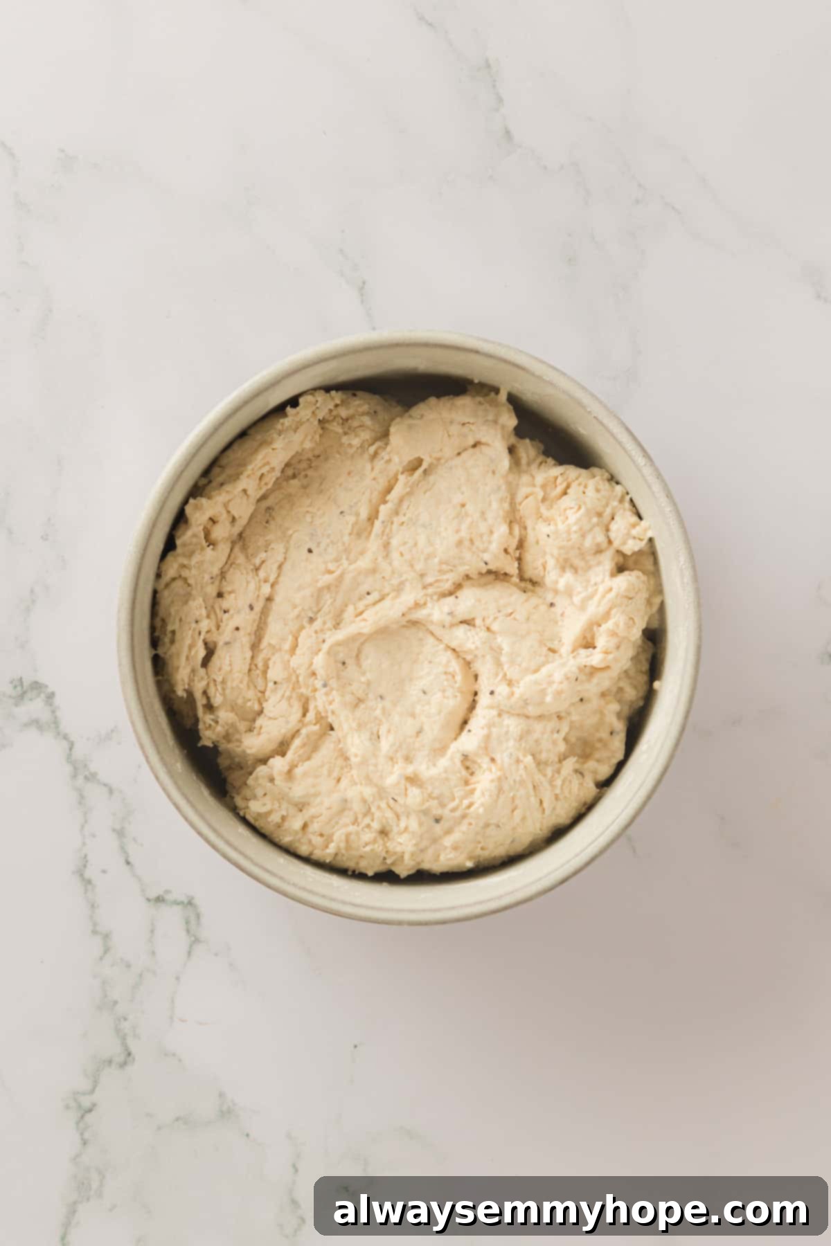 The prepared dumpling dough, sticky and ready for cooking. Close-up of sticky dumpling dough in a mixing bowl, ready to be scooped.
